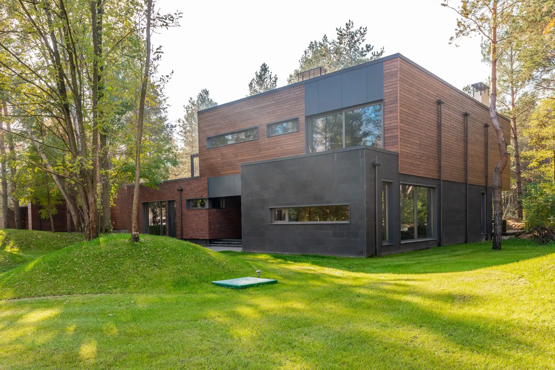 Moderne trehus i to etasjer med kledning i tre og mørk panel